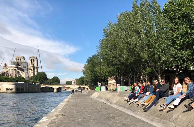 学生们坐在以巴黎圣母院为背景的塞纳河边